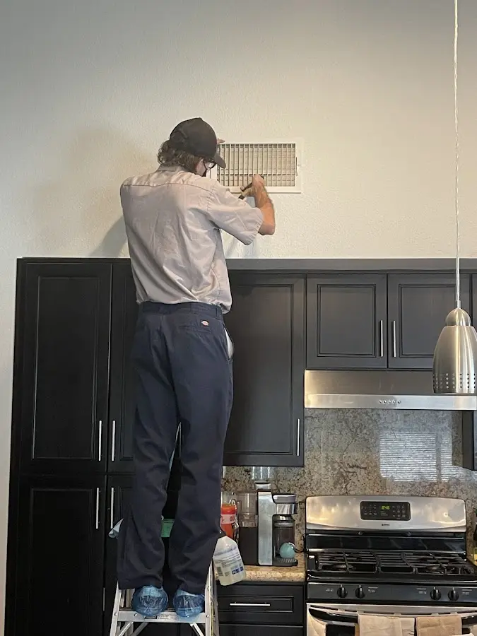 Technician inspecting an air vent during HVAC service in Muscoy